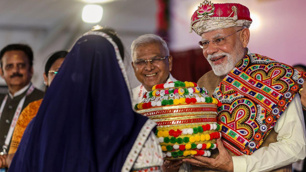 Prime Minister Modi being presented a gift by local woman at the PM MITRA Park foundation stone ceremony.